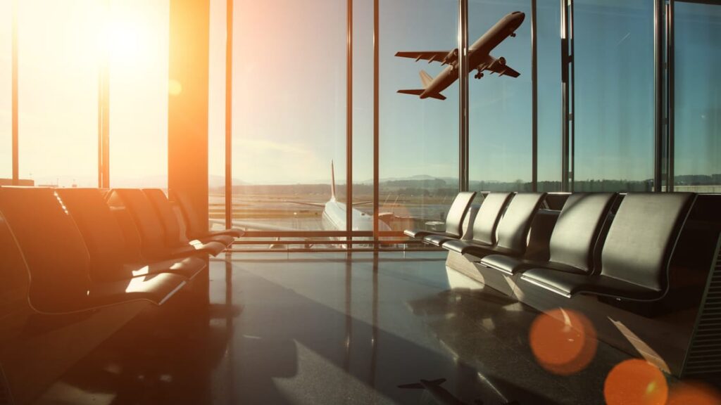 Sala de embarque com avião decolando ao pôr do sol